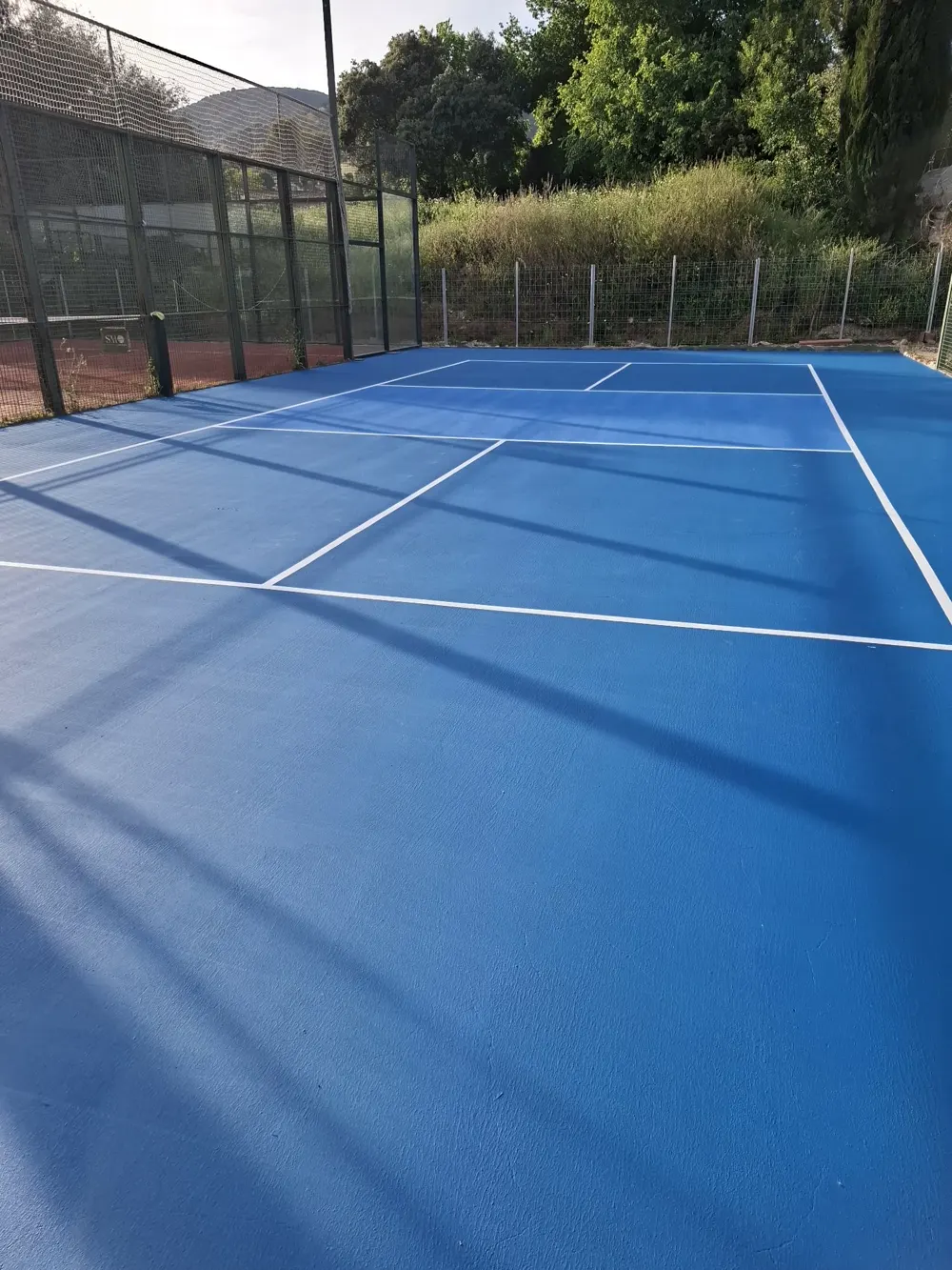Pista deportiva pintada azul con líneas blancas recién terminada — trabajo real de Pulimentos Jiménez