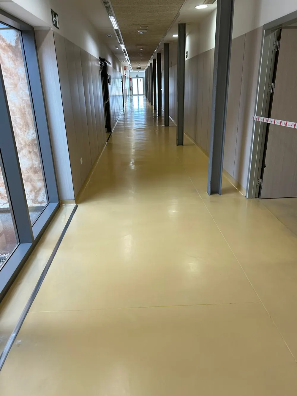 Pasillo largo amarillo brillante sin obstáculos, edificio público — trabajo real de Pulimentos Jiménez