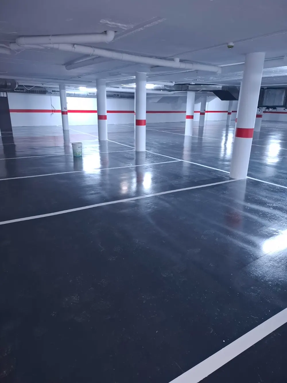 Parking pintado gris oscuro con líneas blancas y pilares — trabajo real de Pulimentos Jiménez