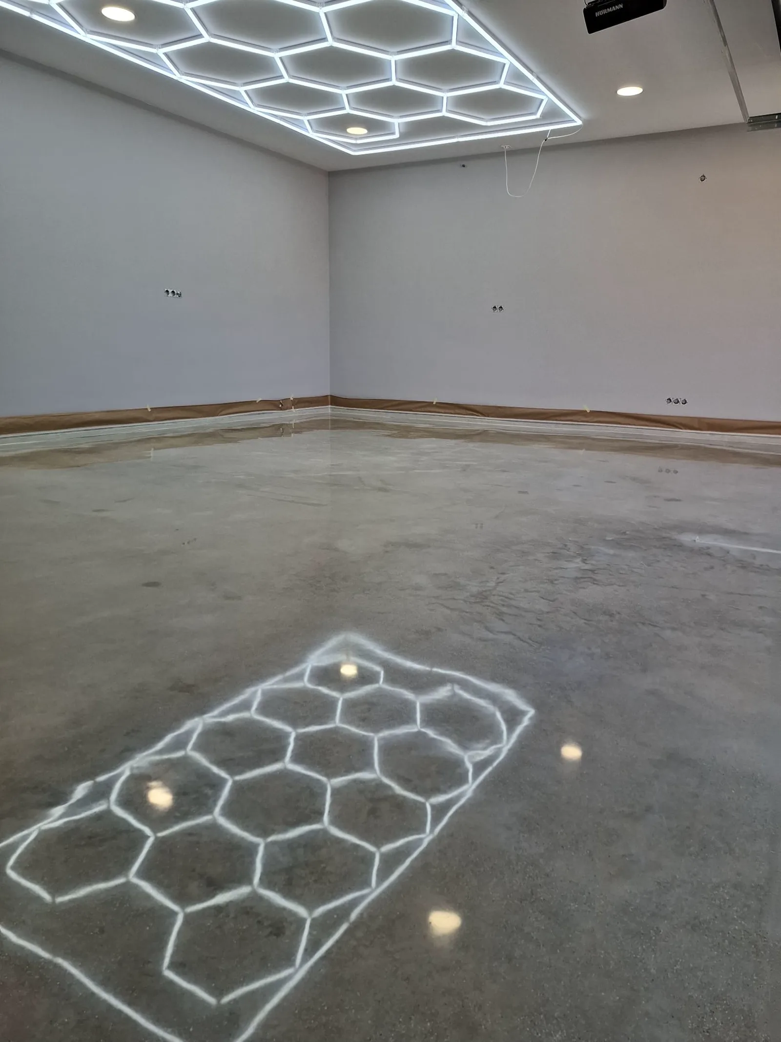 Vista general del garaje con el techo LED hexagonal reflejado en el hormigón pulido
